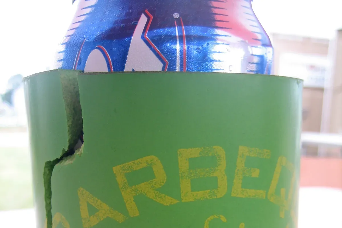 A blue foam can cooler standing on a wooden deck