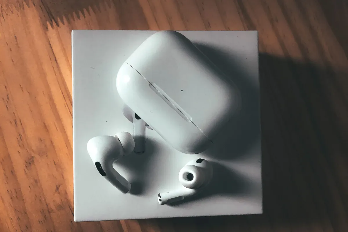 White wireless earbuds next to an open charging case on a wooden table