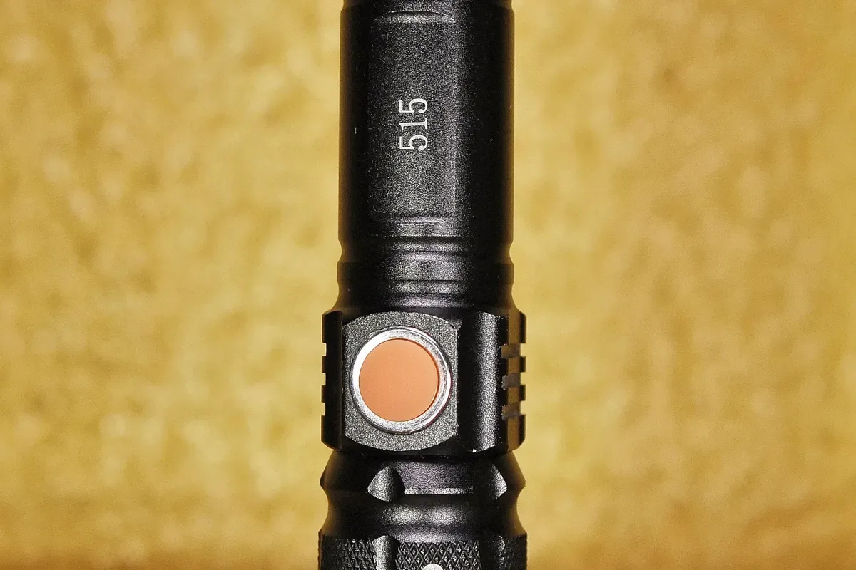 A black flashlight lying on a wooden table