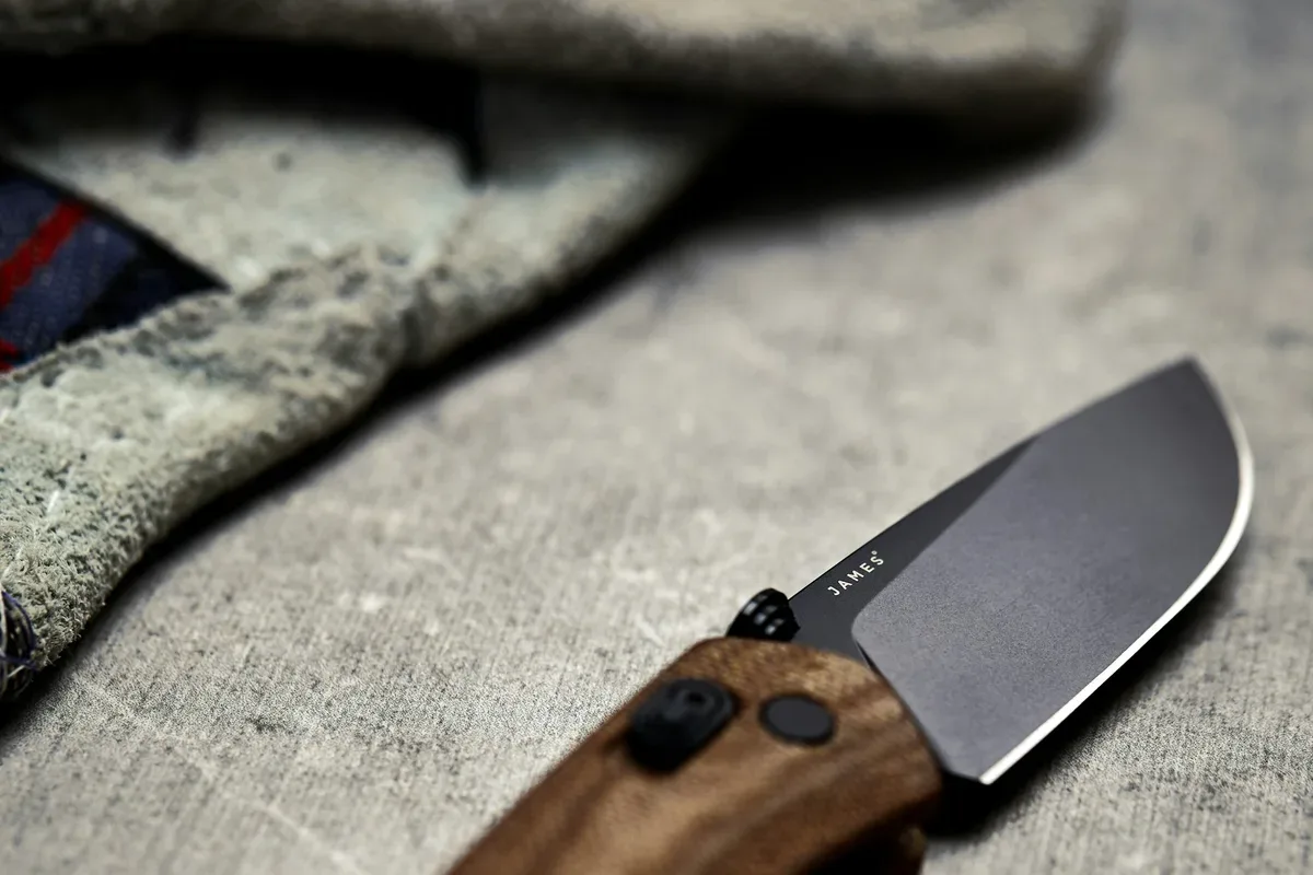 A closed folding pocket knife with a wooden handle on a wooden table