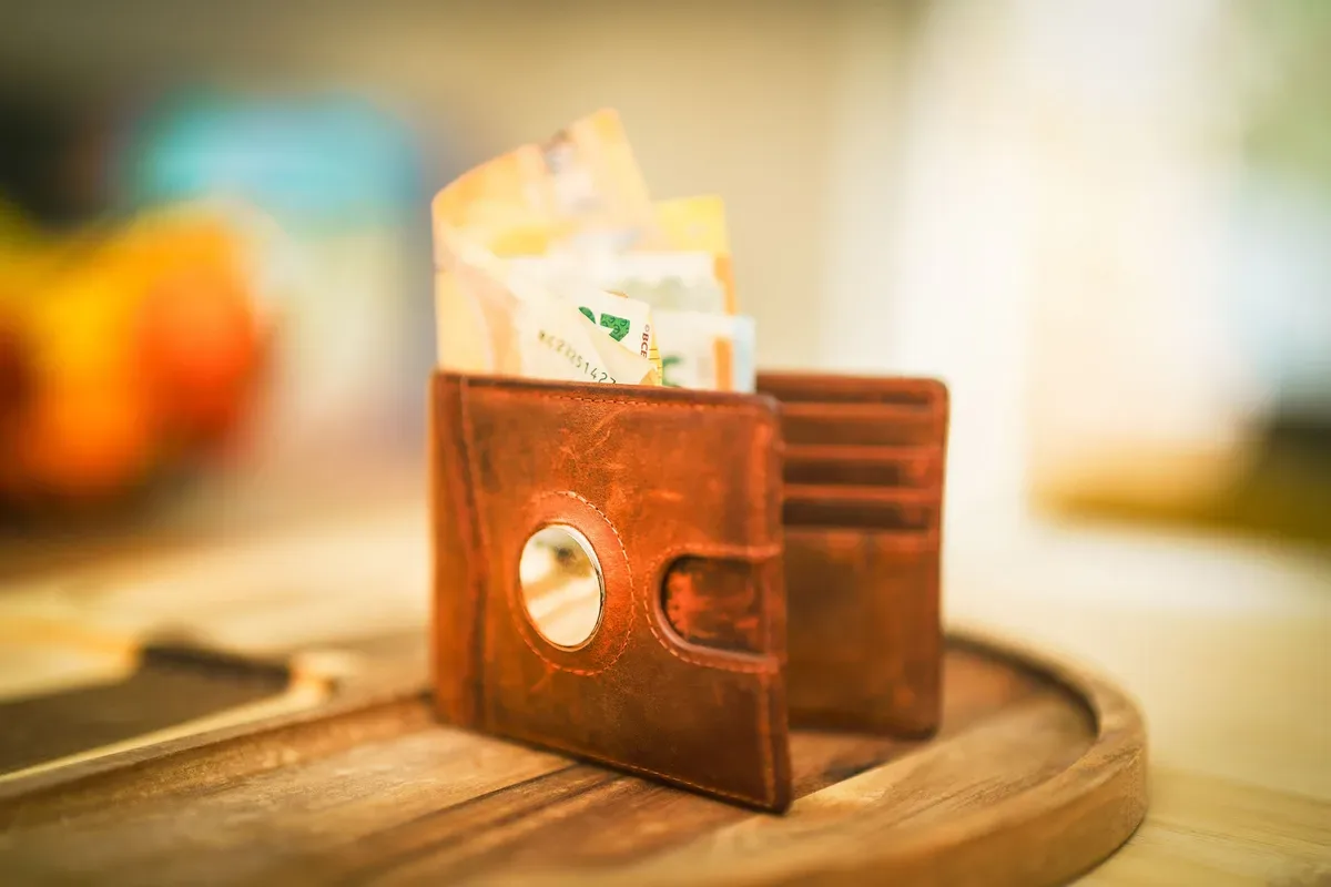 A brown leather wallet open on a wooden table, with cards in the slots