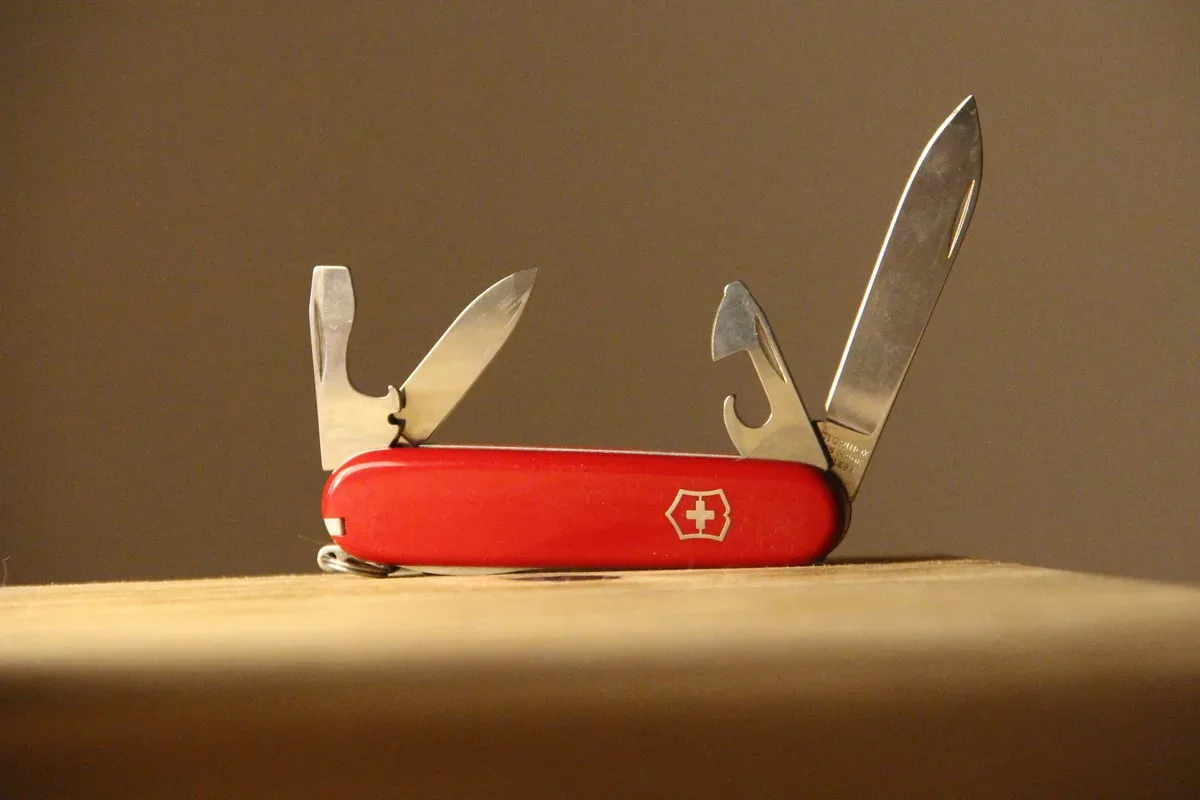 A red pocket multi-tool open on a wooden table